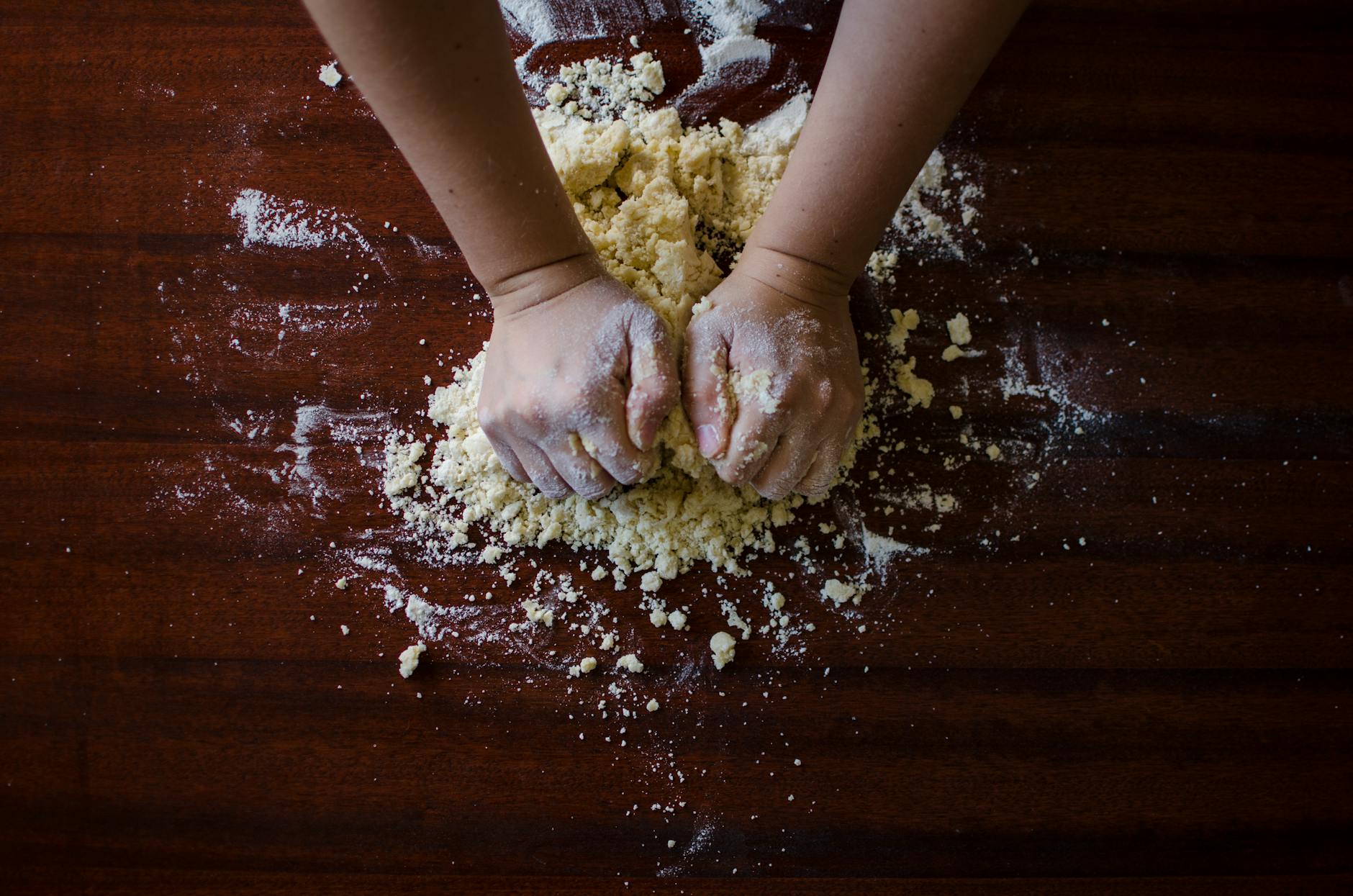 An elderly woman with kind eyes bakes bread in a rustic kitchen bathed in warm light.