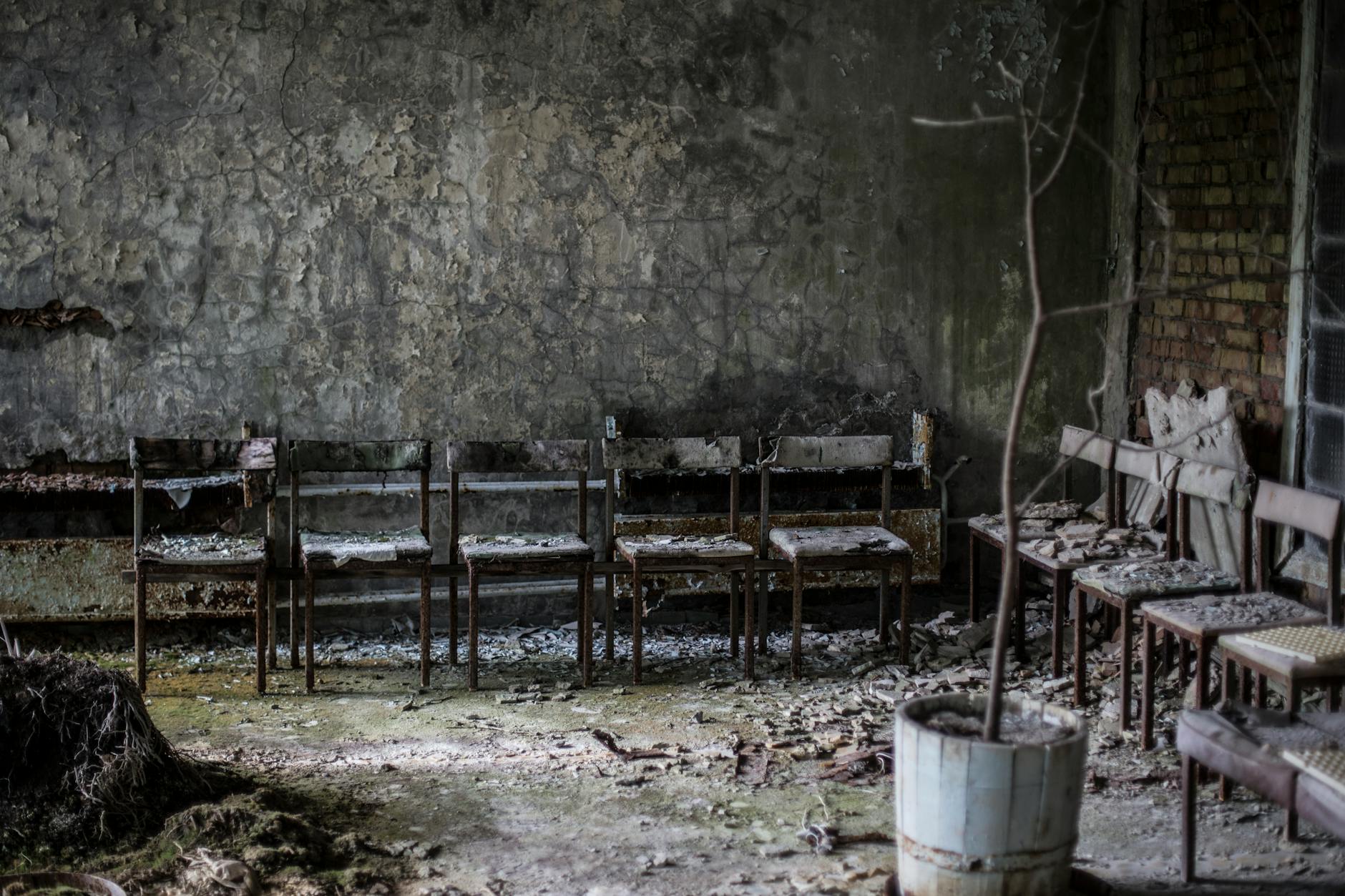 An old man reading in a dimly lit, ruined library, surrounded by scattered books and debris, a single candle illuminating his face.