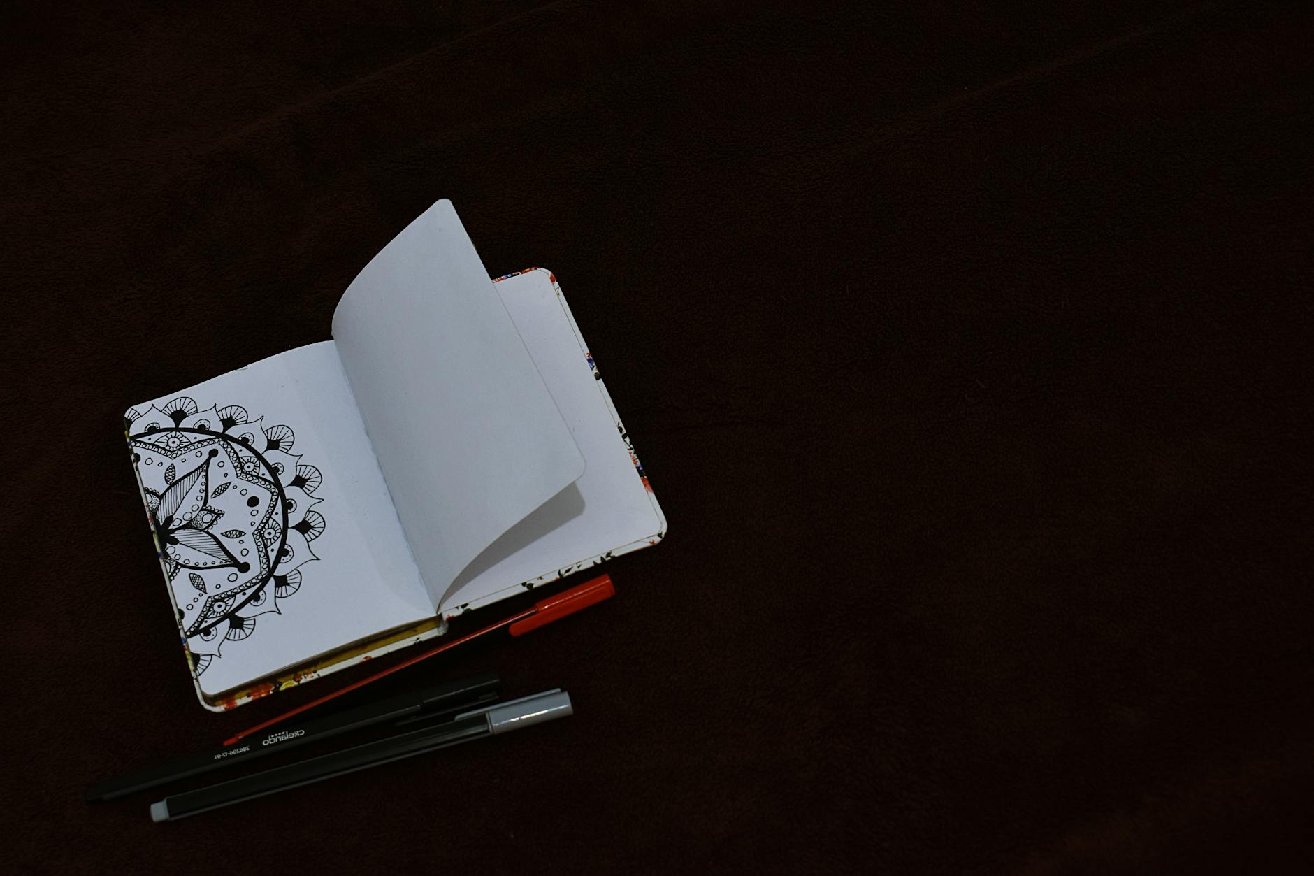 A worn leather-bound journal open to a page filled with intricate drawings of constellations, done in charcoal.
