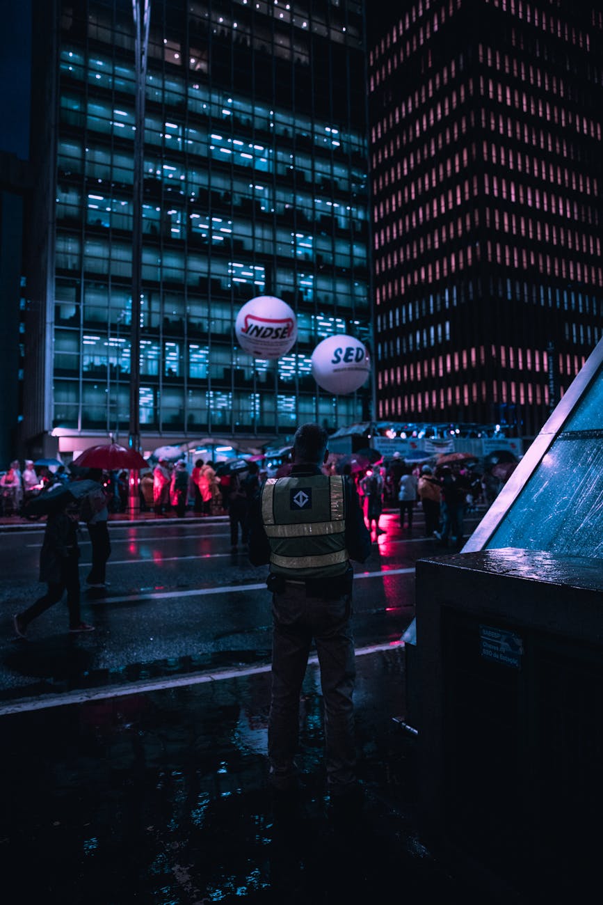 An empty office desk at night with a view of a rain-soaked city, symbolizing loss and a new beginning.