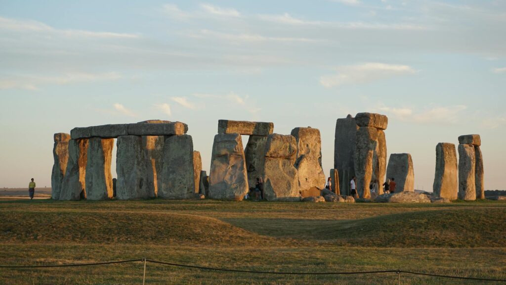 An ancient stone circle covered in snow, with the first rays of the winter solstice sunrise illuminating the stones.